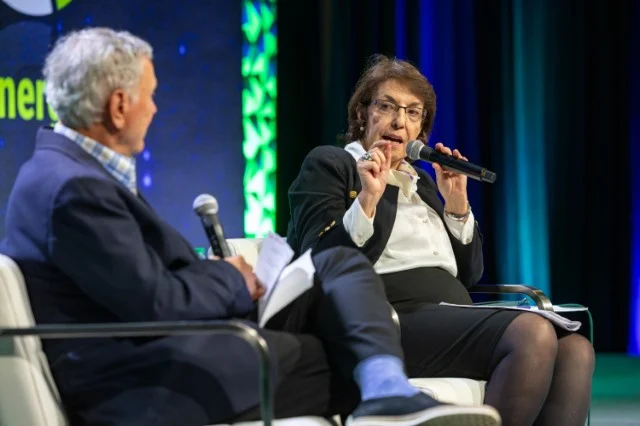 Image of two corporate executives in discussion, while seated on stage at a conference.