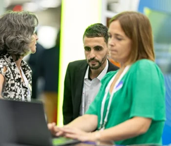 Photo of a geophysicist working on a laptop with another geophysicist looking on.