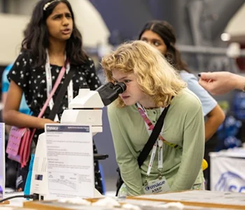 Photo of a young student looking through a microscope